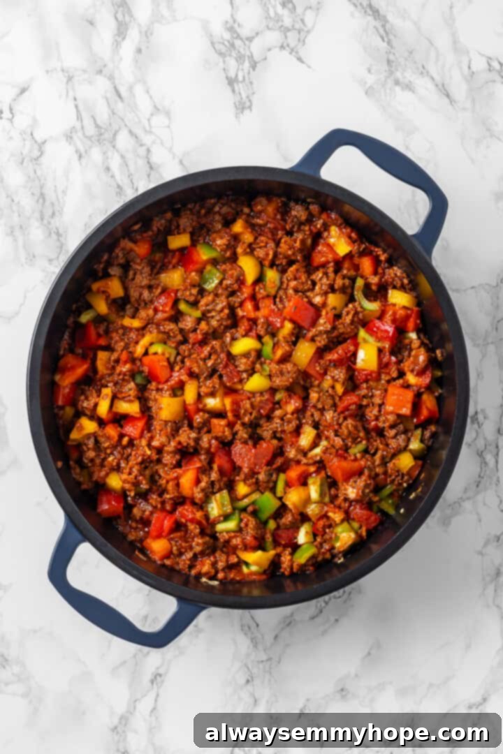 Mixed vegetables and vegan ground beef sautéing in a skillet. Overhead view of vegetables and vegan ground beef in skillet