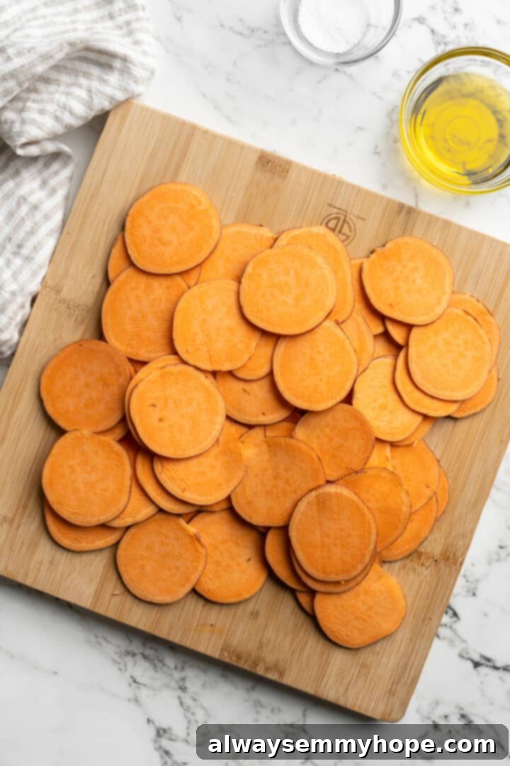 Once you start eating these crispy homemade sweet potato chips, you won’t be able to stop! Super easy to make with only 3 ingredients. Overhead view of neatly sliced sweet potato rounds on a cutting board
