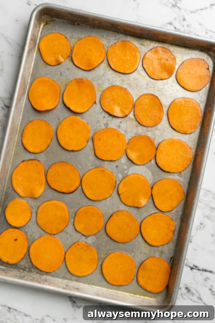 Once you start eating these crispy homemade sweet potato chips, you won’t be able to stop! Super easy to make with only 3 ingredients. Overhead view of olive-oil coated sweet potato slices spread in a single layer on a baking sheet