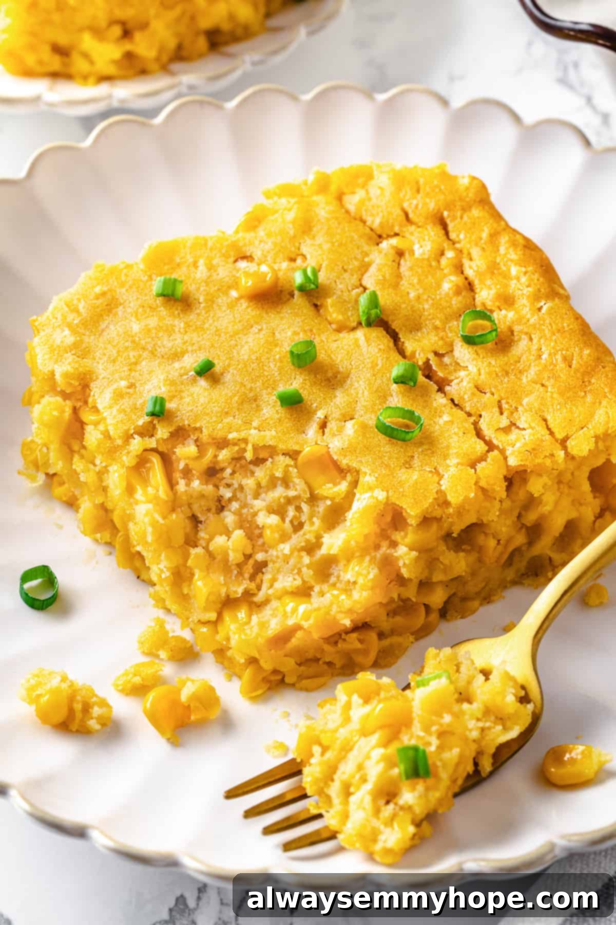 A close-up of a serving of fluffy vegan cornbread pudding on a plate with a fork, emphasizing its delightful texture and golden-brown top.