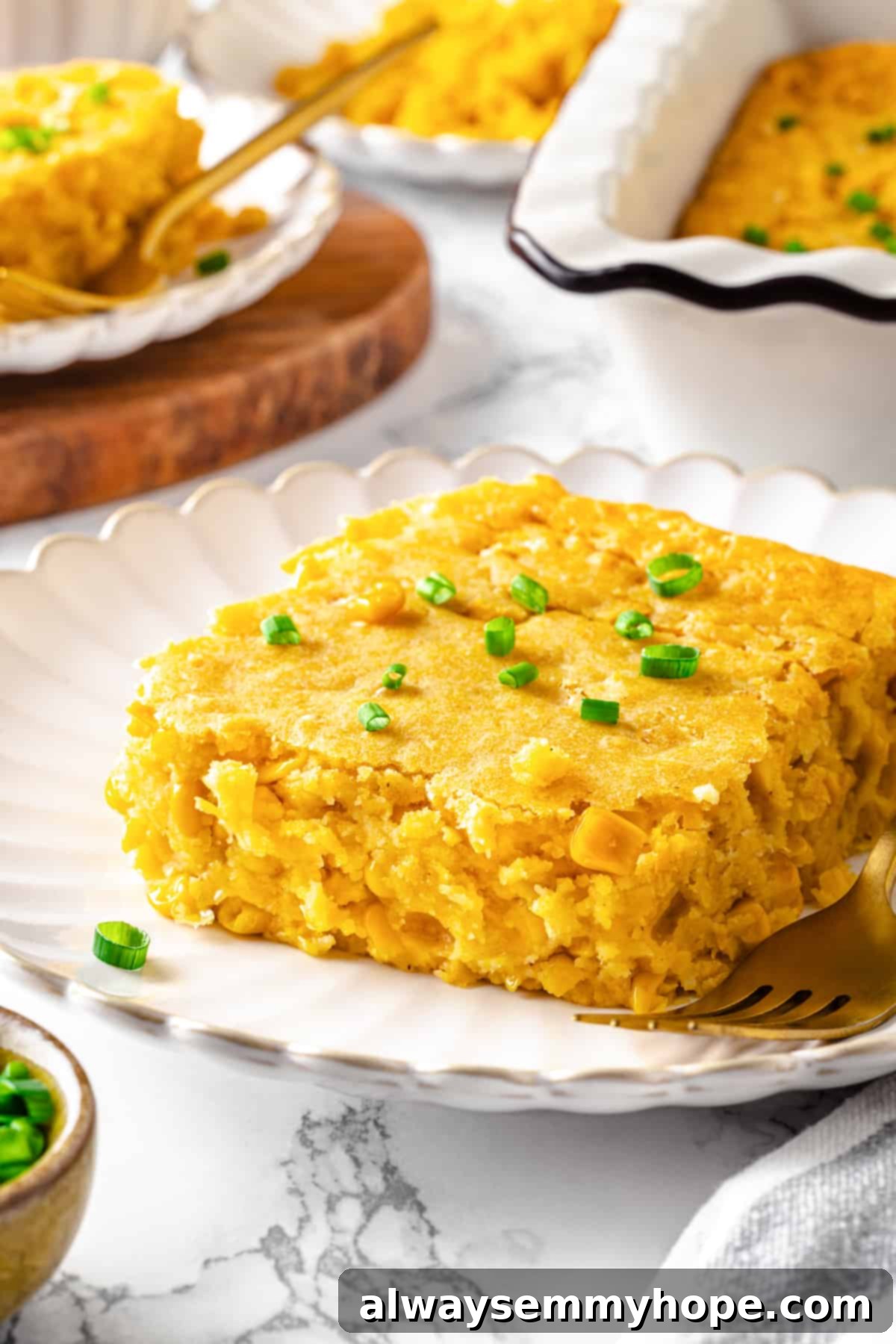 A perfectly portioned serving of vegan cornbread pudding on a white plate, garnished with vibrant green onions, ready to be enjoyed.