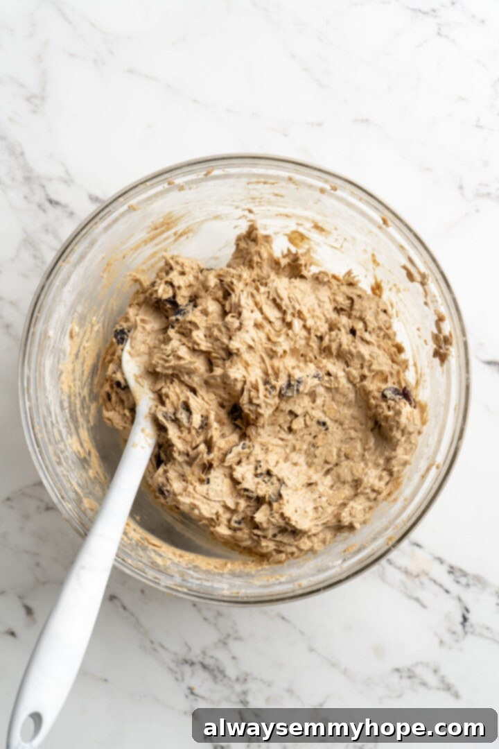 Overhead view of chilled vegan oatmeal raisin cookie dough in a glass mixing bowl