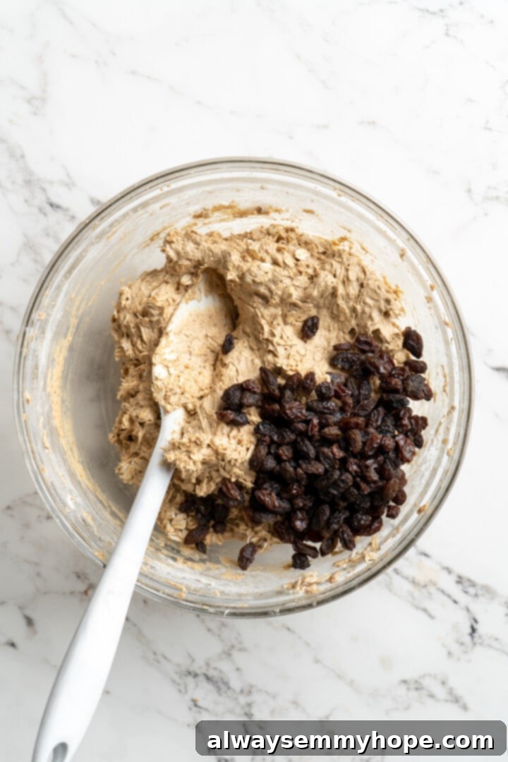 Overhead view of plump raisins added to vegan oatmeal cookie dough, ready to be folded in