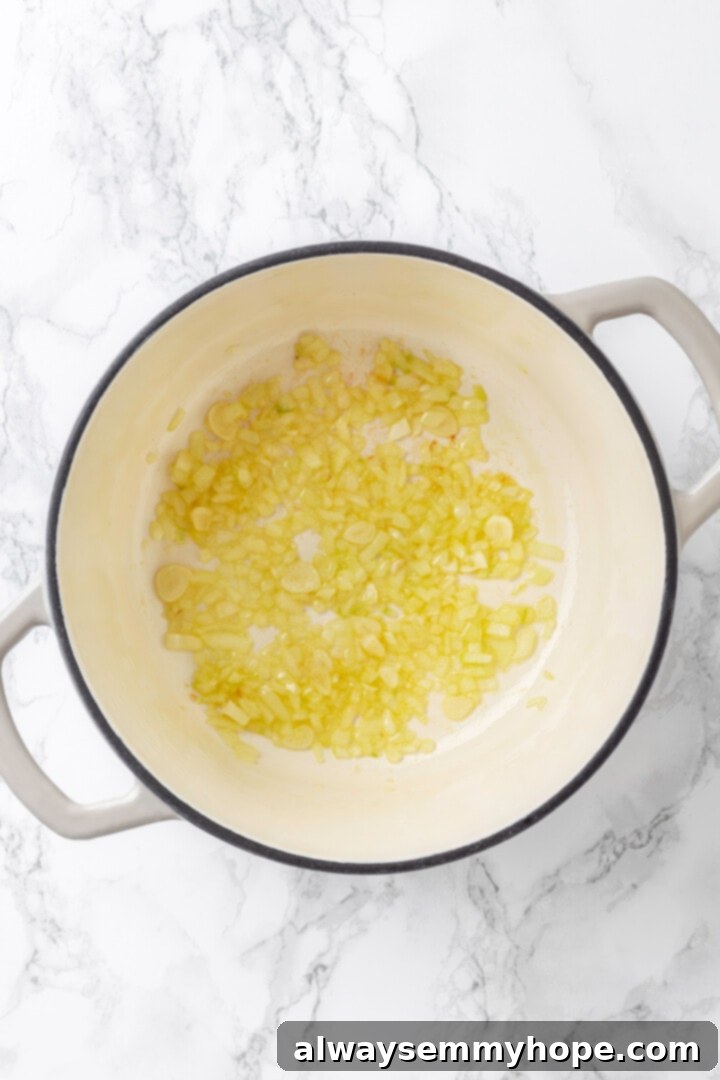 Sautéing onions in olive oil for the rich base of our vegan broccoli cheddar soup! Overhead view of translucent, sautéed onions in a large soup pot with olive oil.