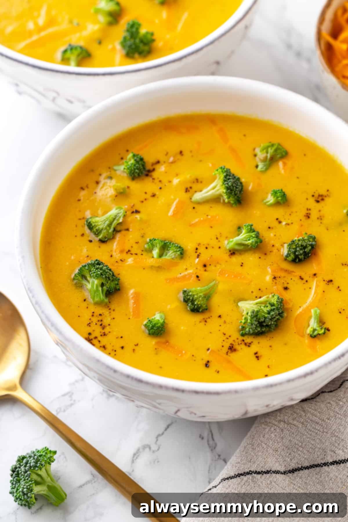 Vegan broccoli cheddar soup in a bowl, garnished with cheese shreds and broccoli florets, ready to be devoured! A bowl of creamy vegan broccoli cheddar soup, elegantly garnished with fresh broccoli florets and a sprinkle of vegan cheese shreds.