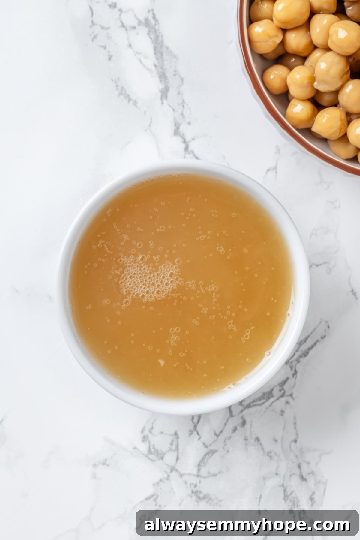 Aquafaba is a miracle worker in vegan baking. But what is aquafaba? And how do you use it? Here’s everything you need to know! Overhead view of chickpea liquid in small white bowl