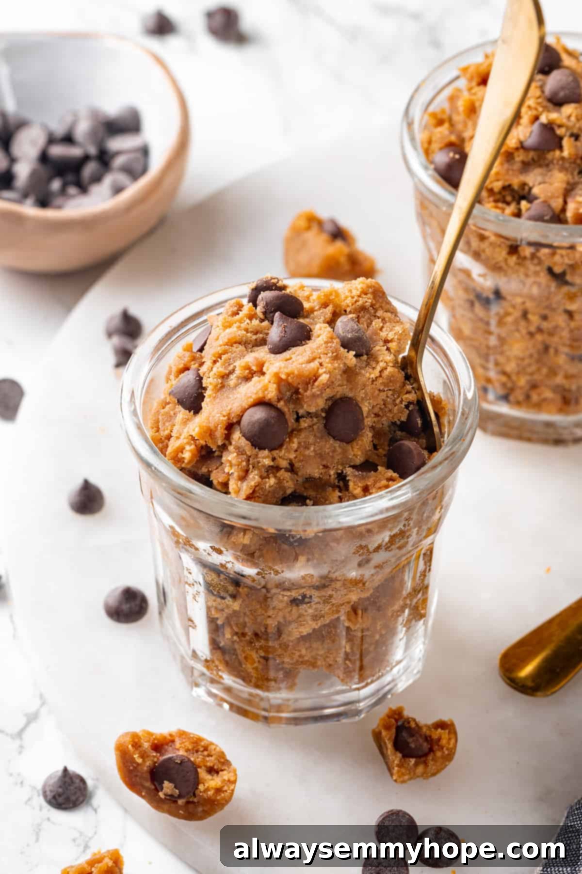 Jar of protein cookie dough with spoon, with another jar of dough in background