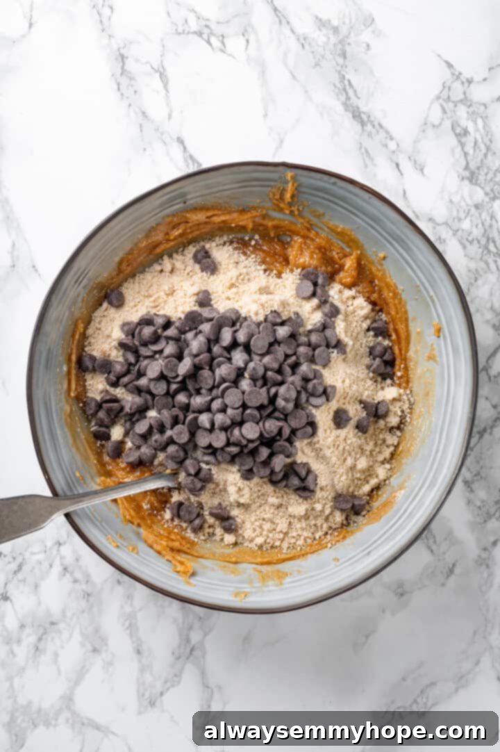 Dry ingredients and chocolate chips added to peanut butter mixture in bowl