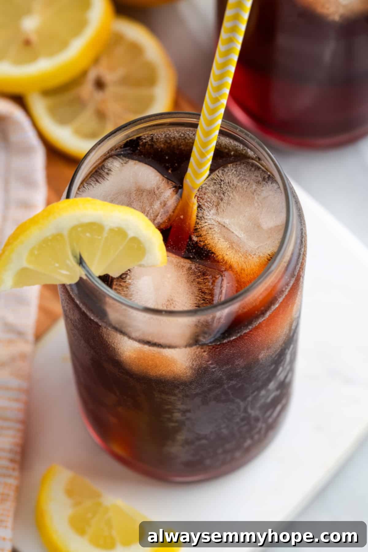 Top down view of a refreshing glass of Southern sweet tea, filled with ice and a straw, elegantly garnished with a lemon wedge on the rim.