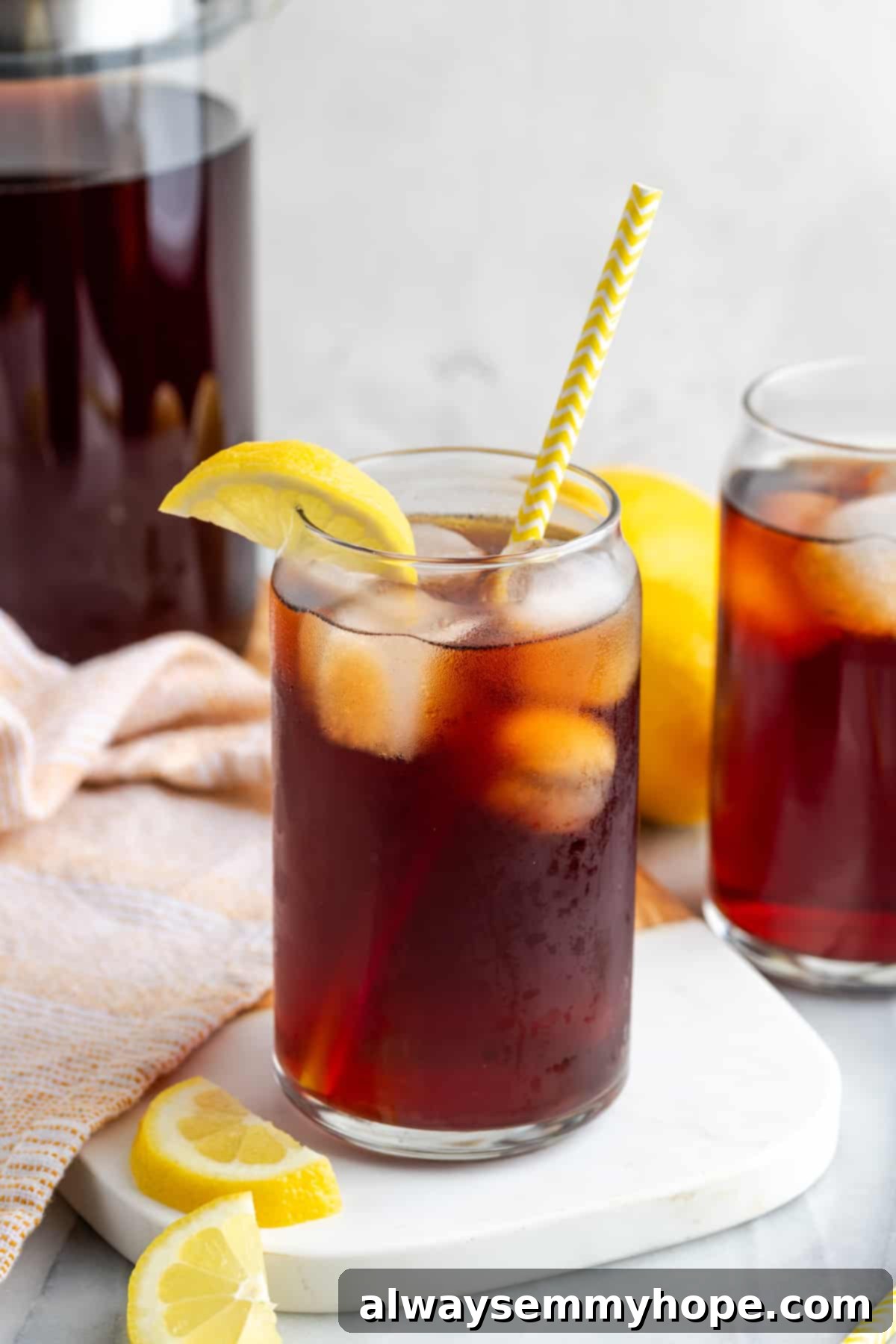 Two glasses of Southern sweet tea, one with a straw and lemon, the other plain, set on a rustic wooden surface, evoking a sense of calm and tradition.