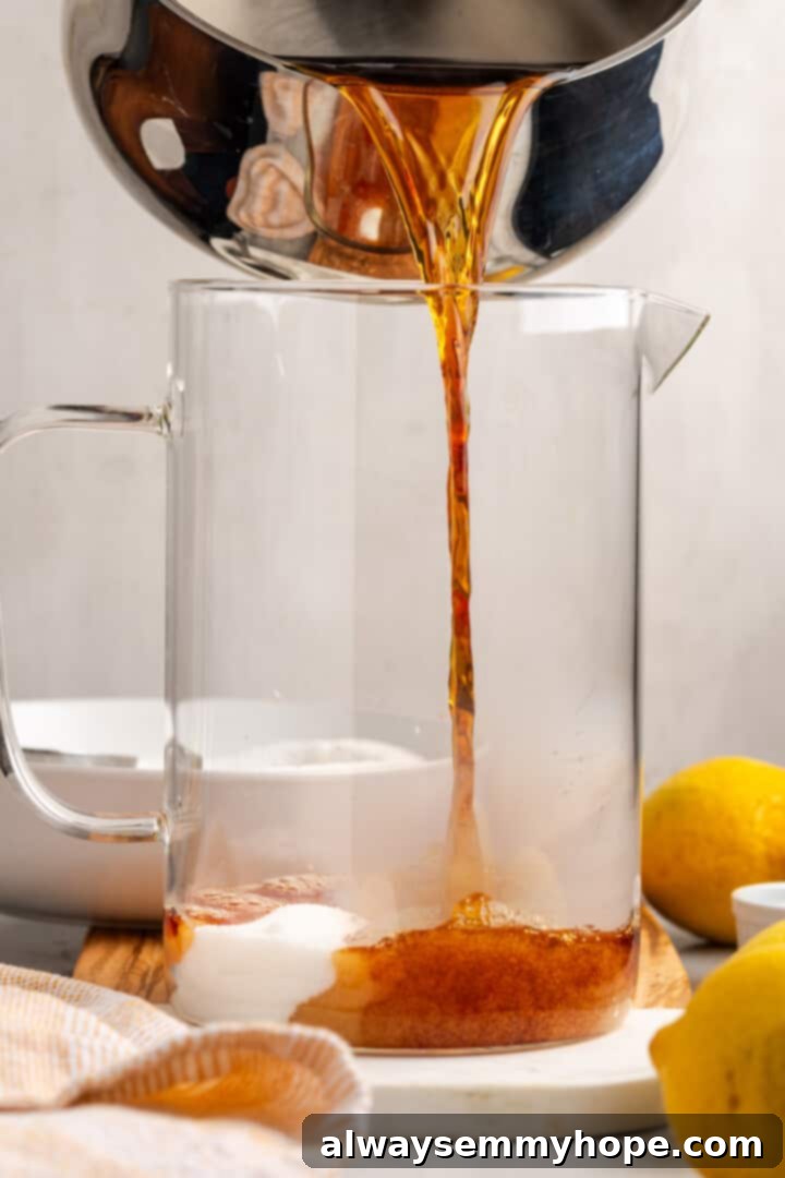 Carefully pouring the freshly steeped tea concentrate into a pitcher already containing sugar and baking soda.