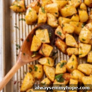 Overhead view of crispy Batata Harra on a baking sheet with a wooden spoon, ready to be served.