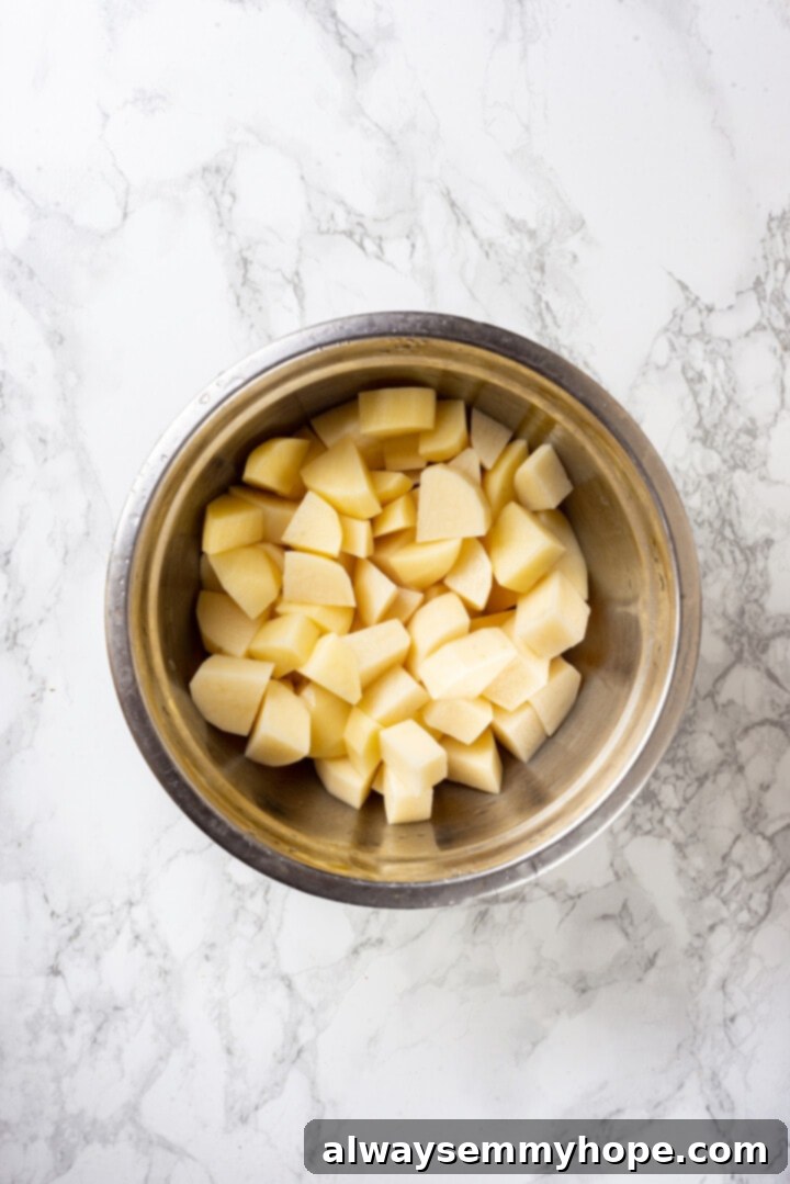 Overhead view of peeled and diced potatoes in a mixing bowl, ready for seasoning.