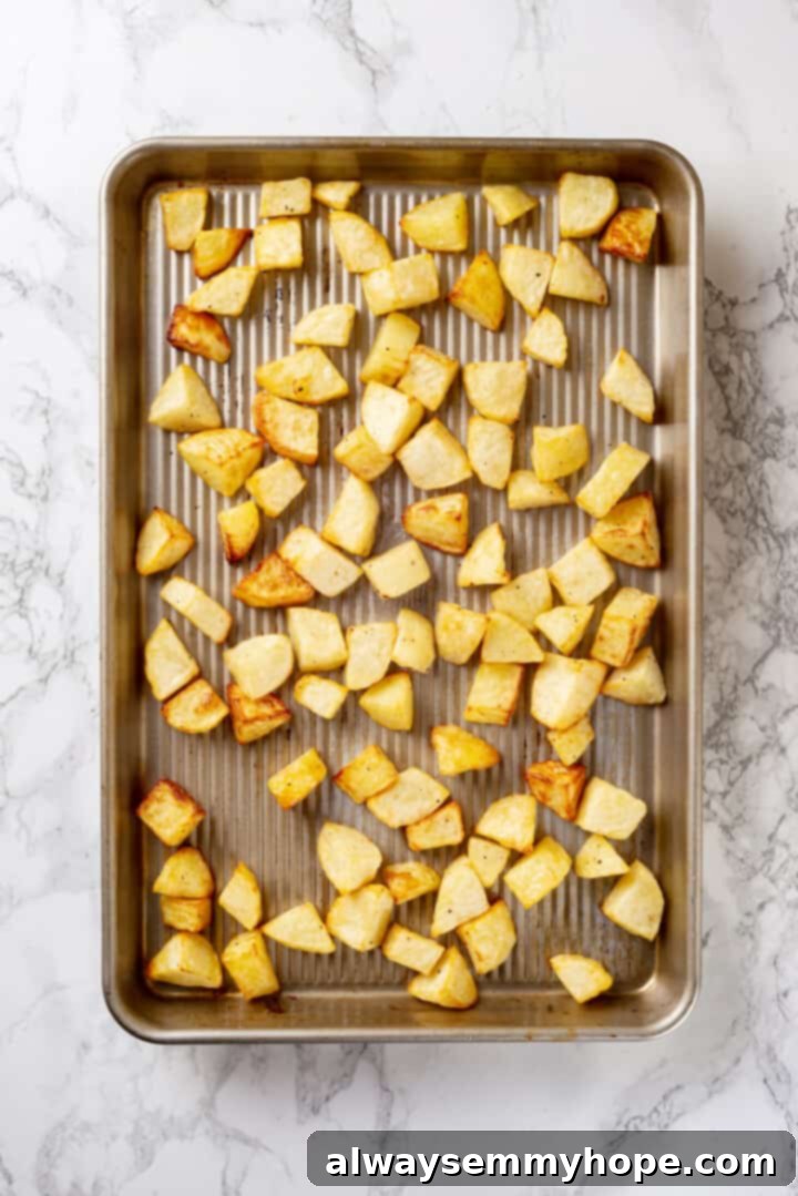 Overhead view of golden-brown and crispy roasted potatoes fresh out of the oven, still on the baking sheet.