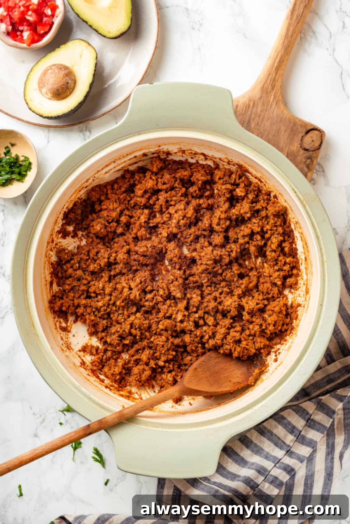 Overhead view of the finished soyrizo in a pan, being stirred with a wooden spoon, highlighting its rich color and texture.