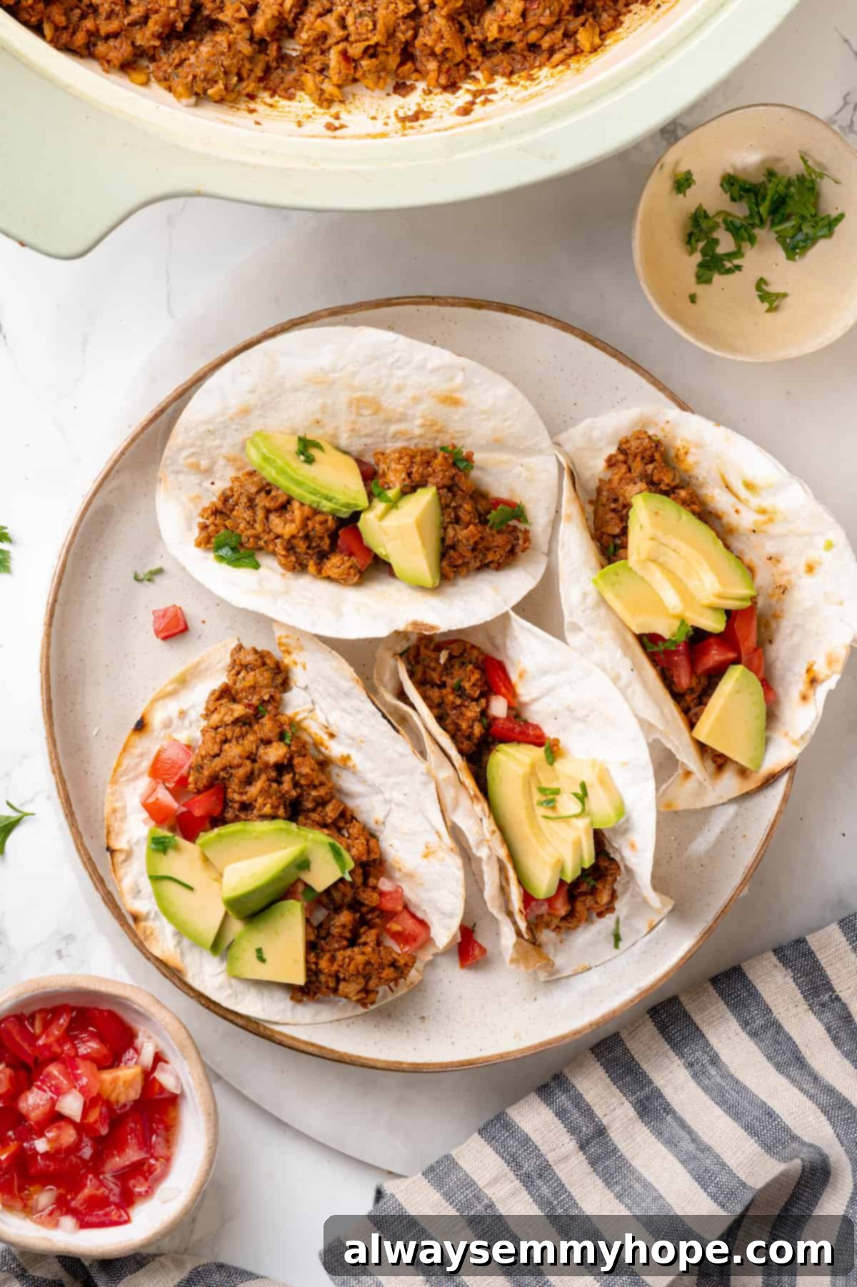 Overhead view of two vibrant soyrizo tacos on a plate, garnished with fresh avocado slices and cilantro.