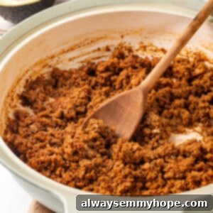 A pan of homemade soyrizo being stirred with a wooden spoon, ready to serve.