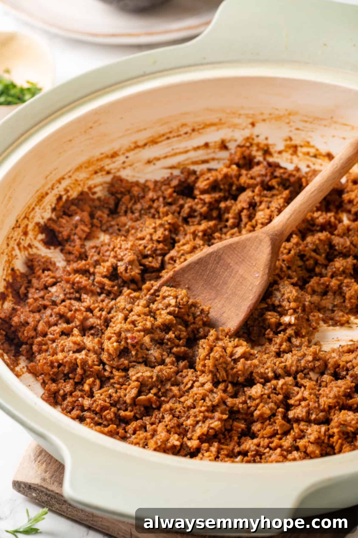 A pan of freshly cooked soyrizo, being stirred with a wooden spoon, showcasing its rich texture and color.