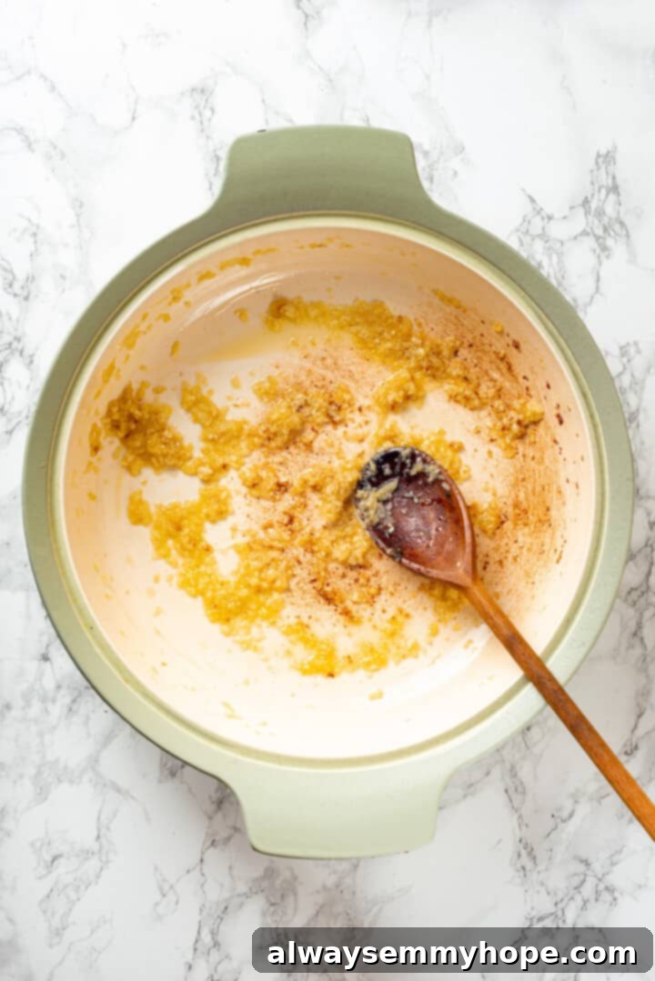 Overhead view of finely minced onions and garlic sautéing in olive oil in a pan.