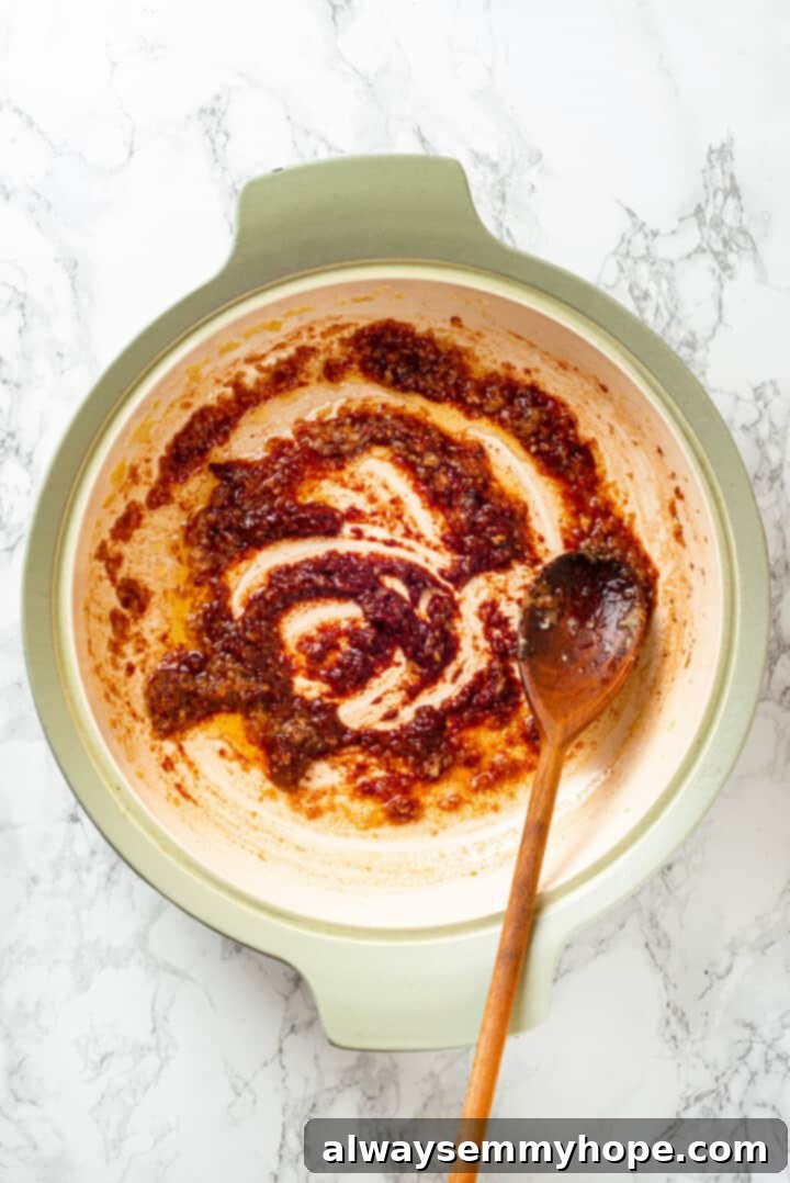Overhead view of the rich, reddish-brown sauce for the soyrizo, cooking in a pan.