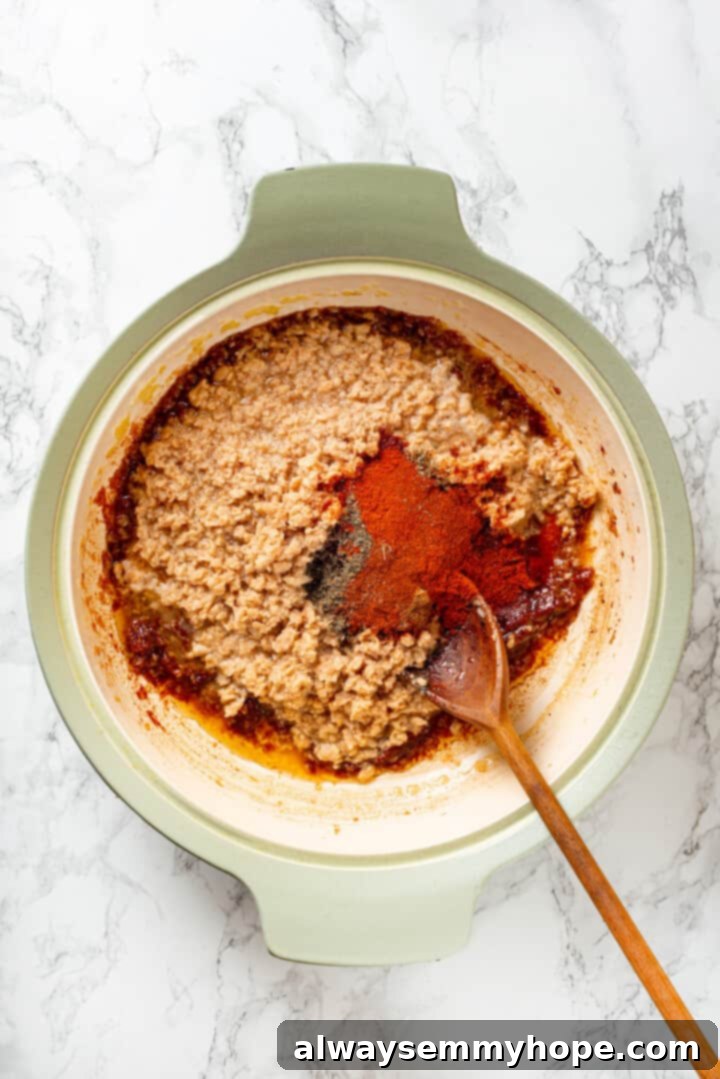Overhead view of the rehydrated TVP and all the spices being stirred into the flavorful sauce in the pan.