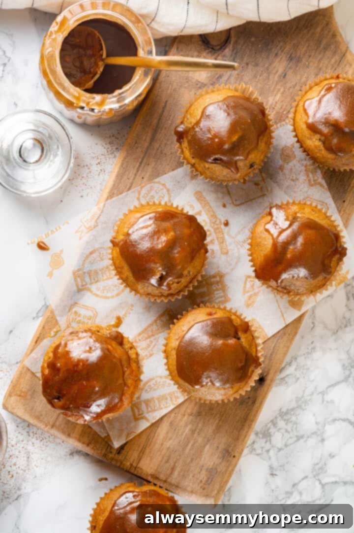 Freshly Glazed Pumpkin Banana Muffins Overhead view of freshly glazed pumpkin banana muffins on a wooden board, ready to serve.