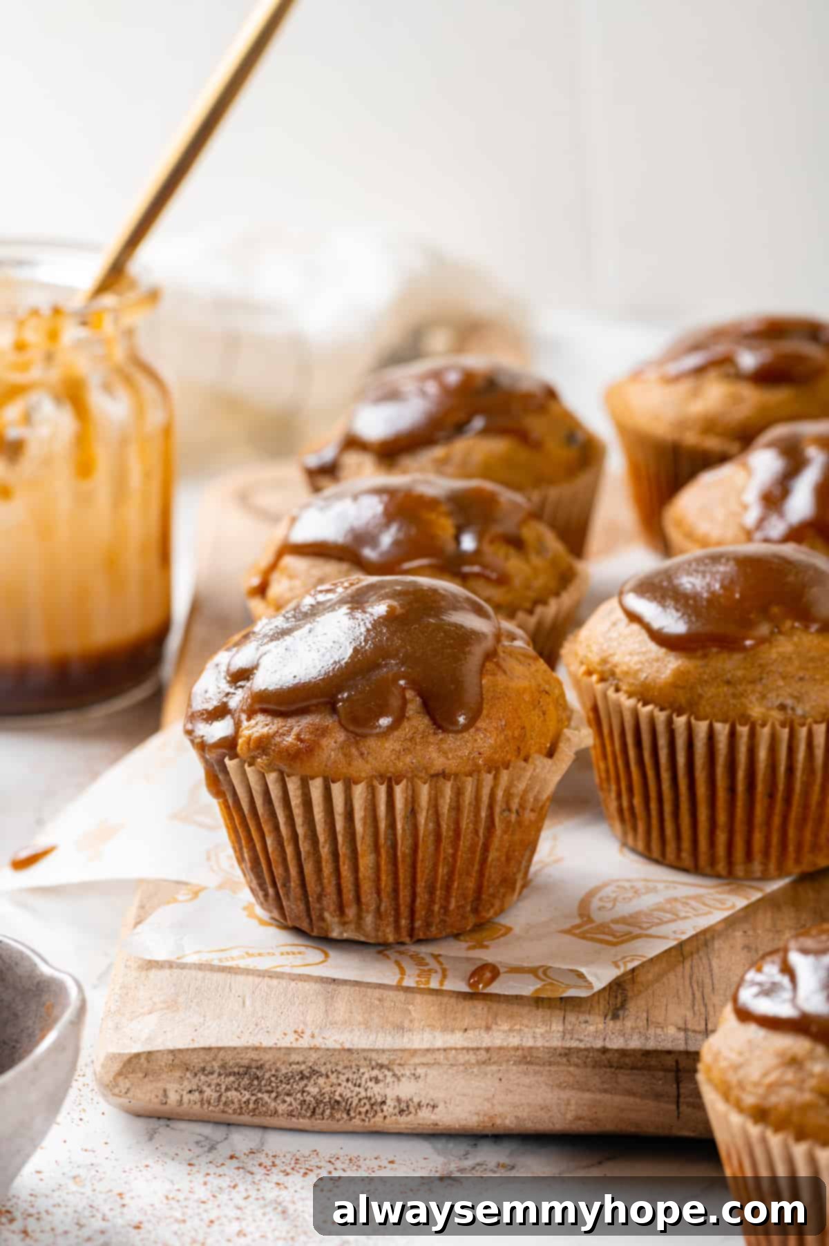 Pumpkin Banana Muffins with Glaze Glazed pumpkin banana muffins arranged appealingly on a wooden board, ready to be enjoyed.