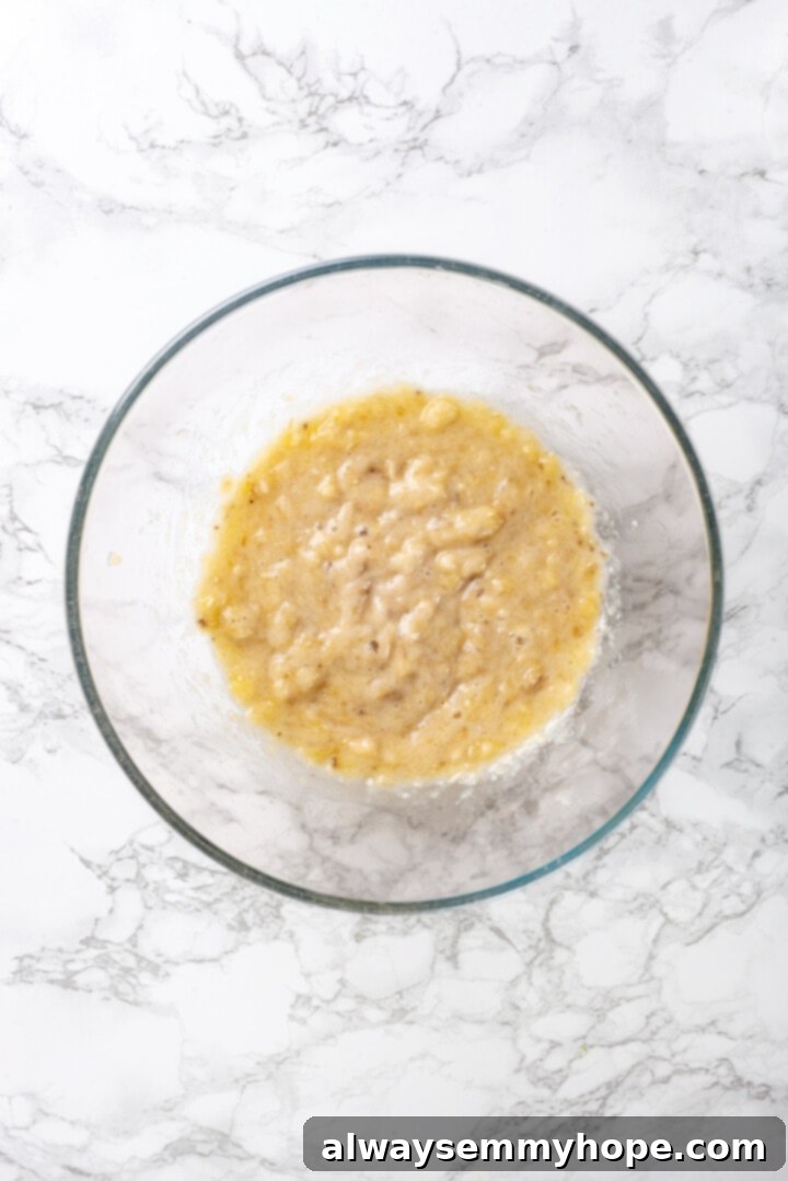 Mashed Banana Prepared for Muffins Overhead view of mashed ripe banana in a clear glass bowl, ready for mixing.