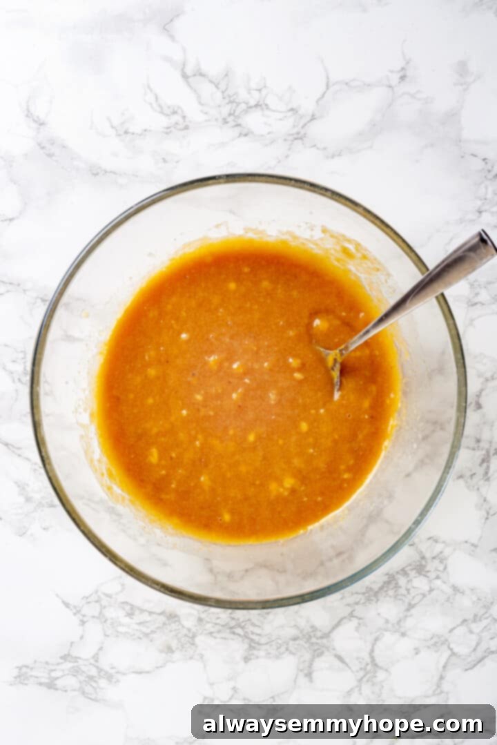 Mixed Wet Ingredients for Muffins Overhead view of thoroughly mixed wet ingredients for muffins in a glass bowl with a spoon.