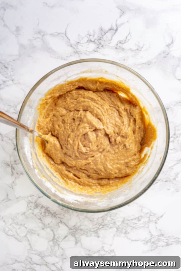 Prepared Muffin Batter Overhead view of prepared muffin batter in a glass bowl with a spoon, showing its smooth consistency.