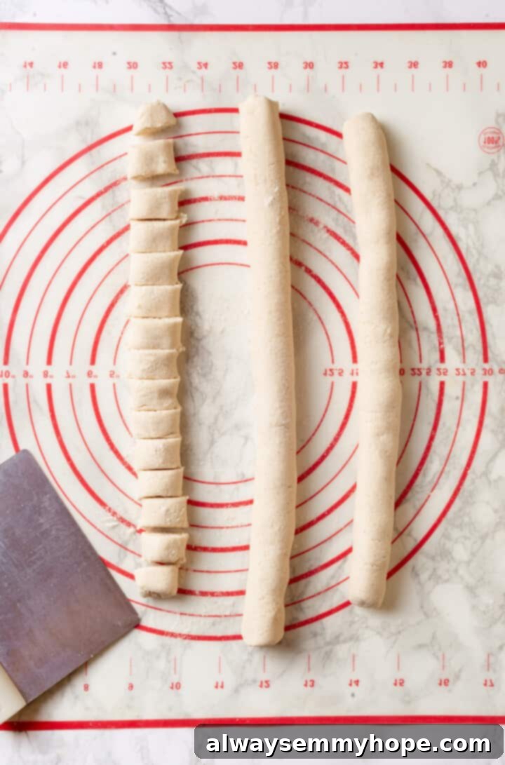 Overhead view of logs of gnocchi dough, with one log cut into gnocchi