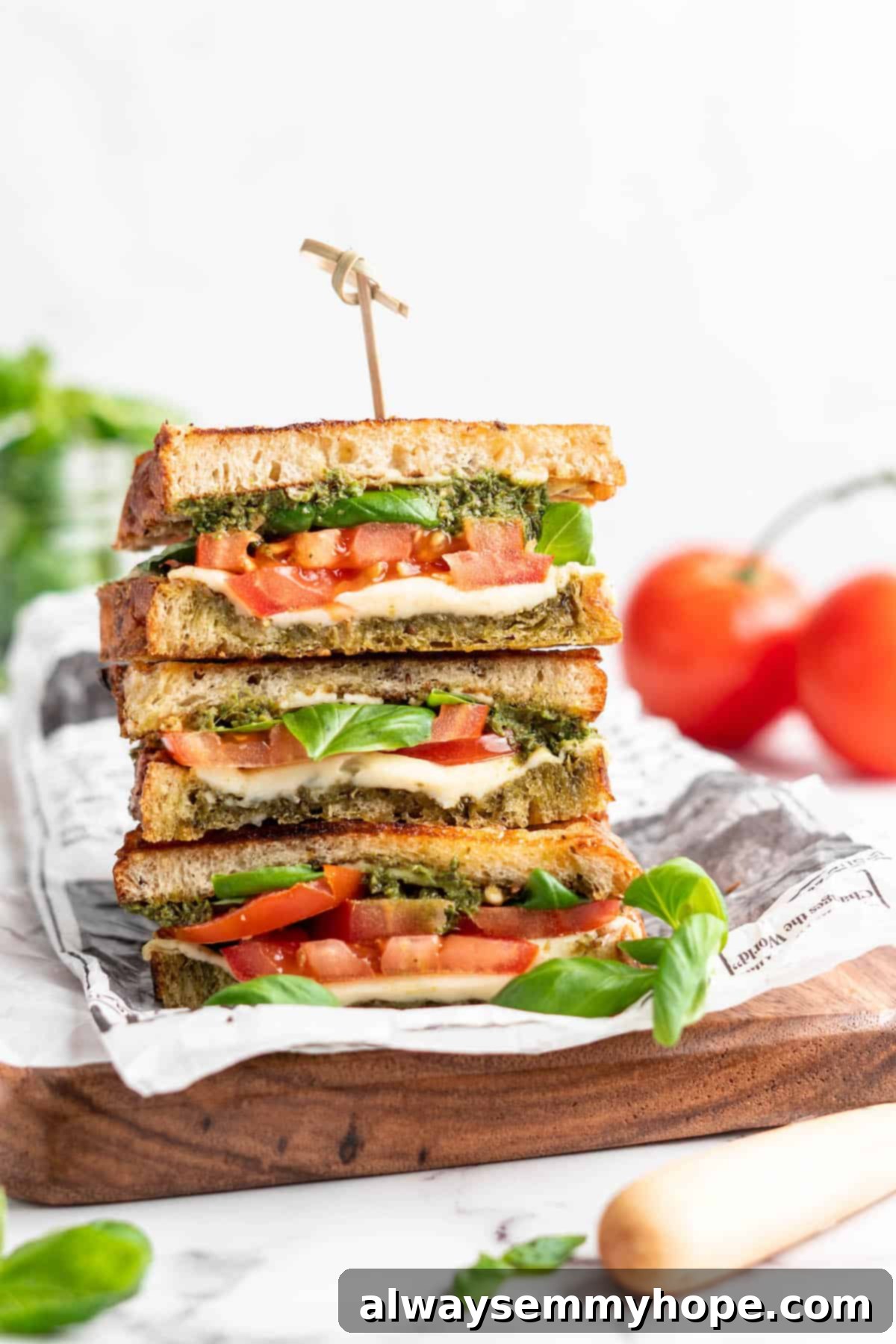 Three stacked vegan caprese sandwiches set on wooden cutting board