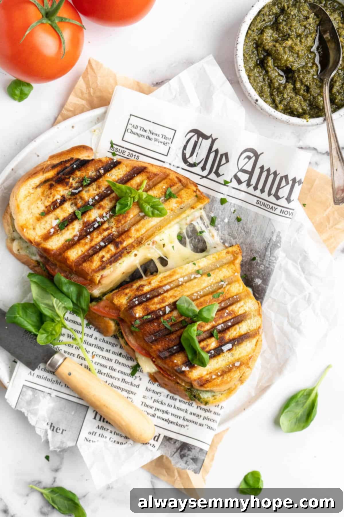 Halved vegan caprese panini, pulled apart to show stretching cheese