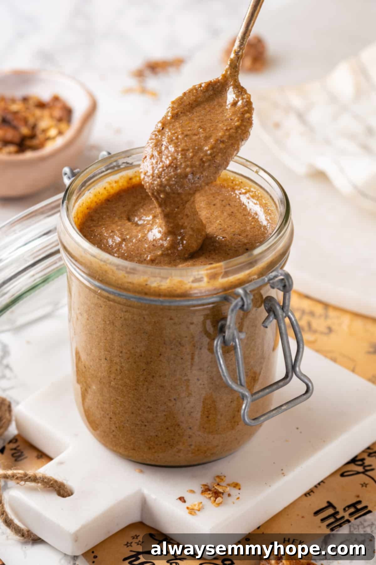 This easy homemade granola butter recipe is a toasty blend of oats, seeds, nuts and cozy spices. Spread it on toast, fruit, waffles and more! Spoon drizzling homemade granola butter back into jar