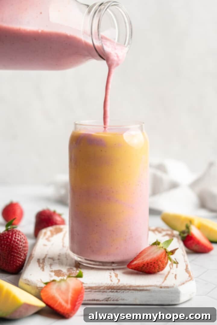 Layered strawberry mango smoothie, with strawberry layer being poured in