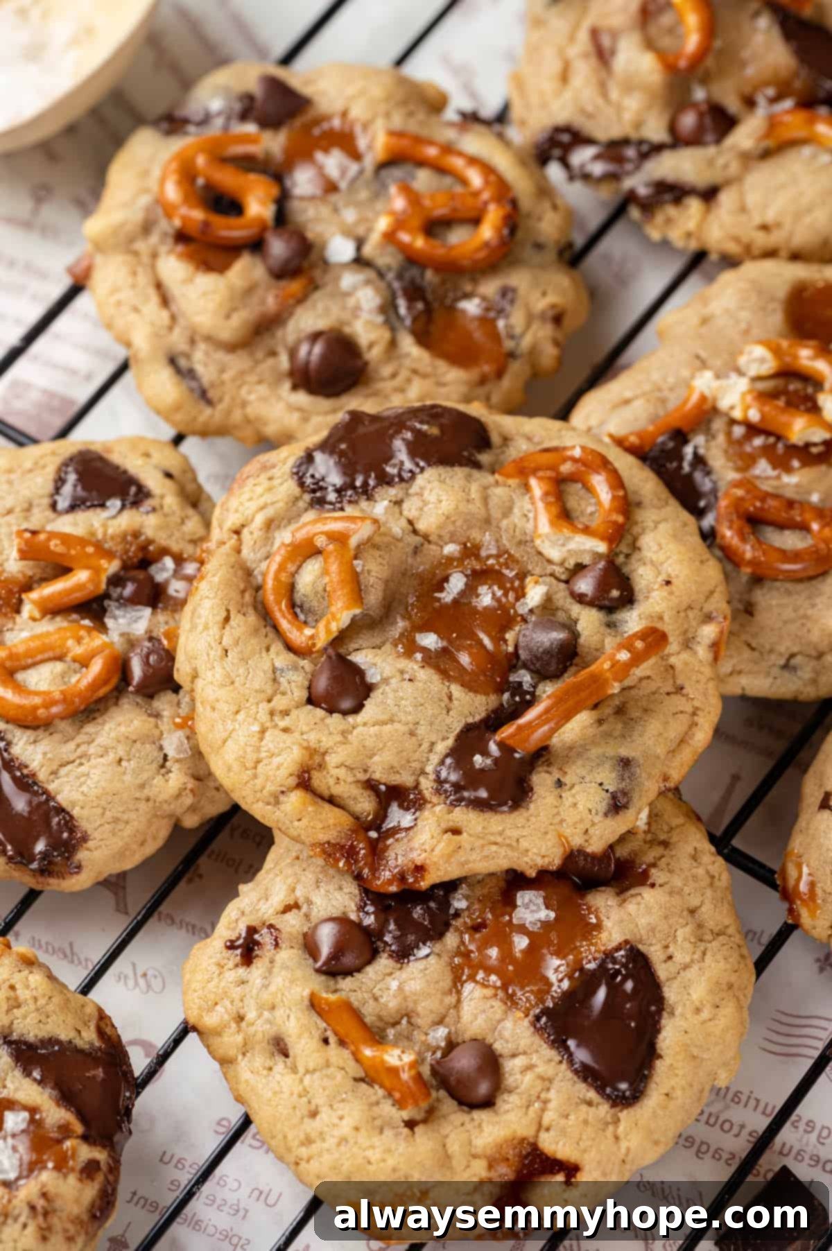 With an irresistible mix of chocolate, caramel and crispy pretzels, these kitchen sink cookies are easy to whip up and even easier to devour! Stack of vegan kitchen sink cookies on cooling rack, showcasing their diverse mix-ins.