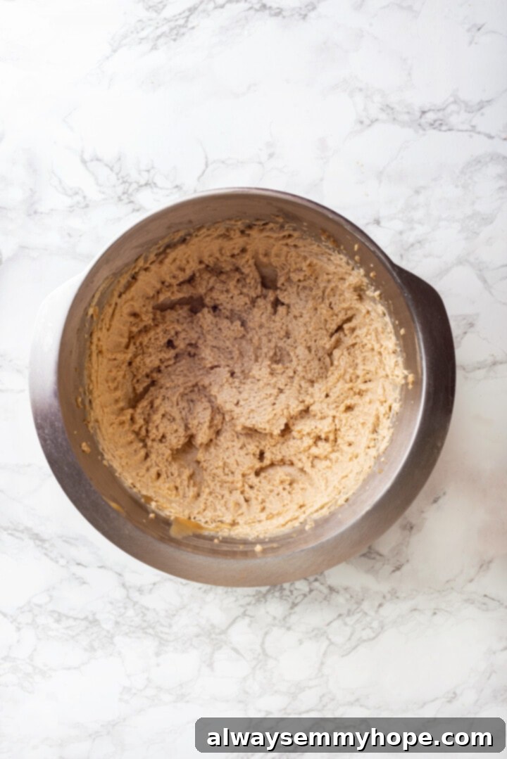 With an irresistible mix of chocolate, caramel and crispy pretzels, these kitchen sink cookies are easy to whip up and even easier to devour! Overhead view of dry ingredients, including flour, baking soda, and salt, being added to the wet ingredients in a mixer bowl.