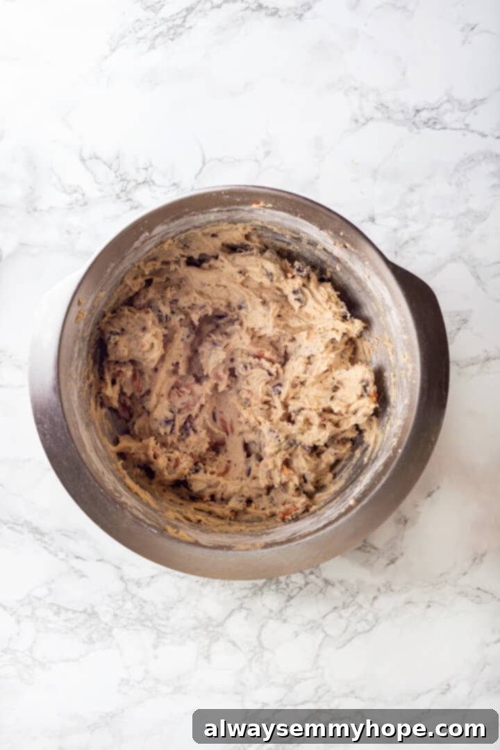 With an irresistible mix of chocolate, caramel and crispy pretzels, these kitchen sink cookies are easy to whip up and even easier to devour! Overhead view of the finished vegan kitchen sink cookie dough in a bowl, generously filled with various mix-ins.