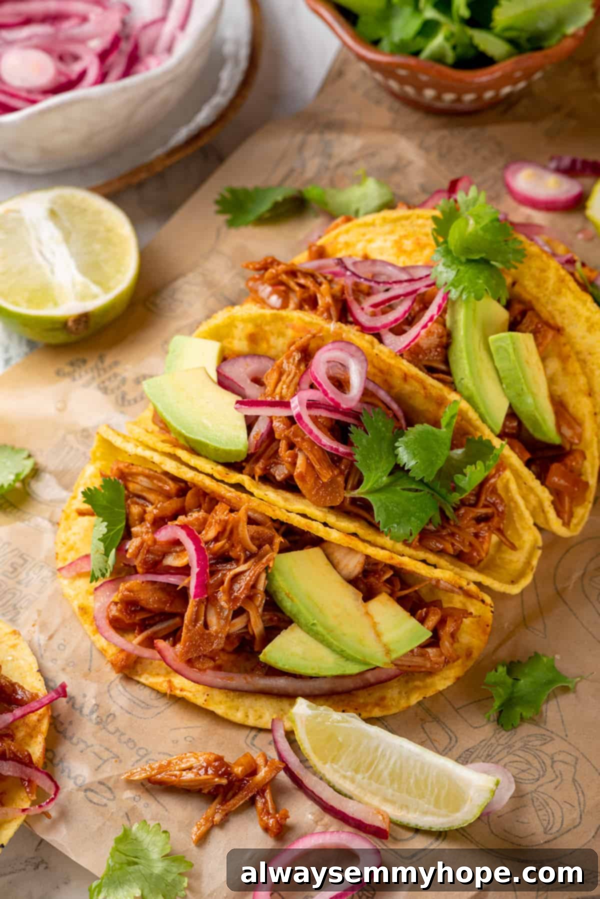 4 jackfruit tacos on parchment paper surrounded by toppings