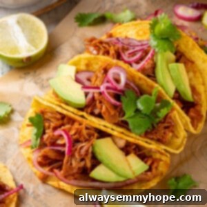 4 jackfruit tacos on parchment paper surrounded by toppings