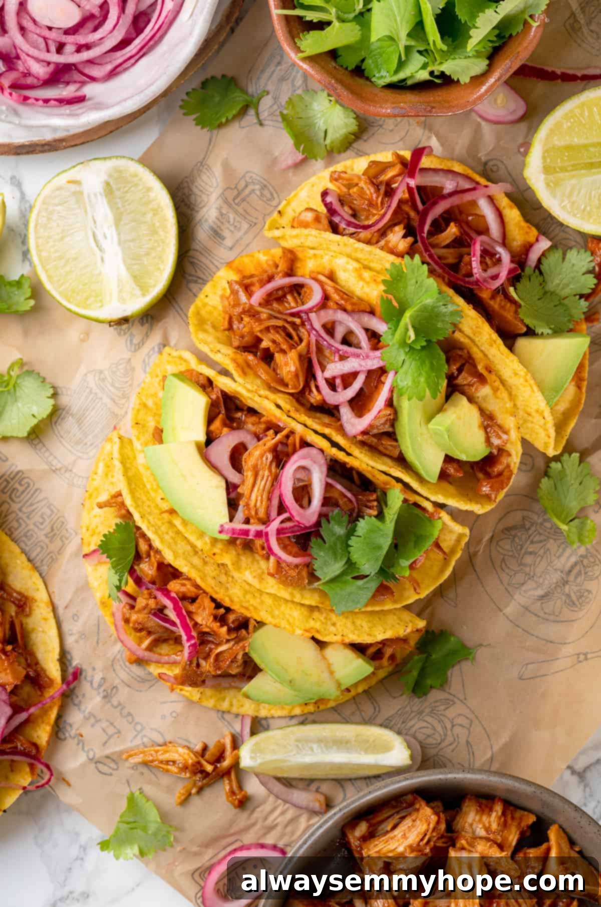 4 jackfruit tacos on printed parchment paper surrounded by toppings