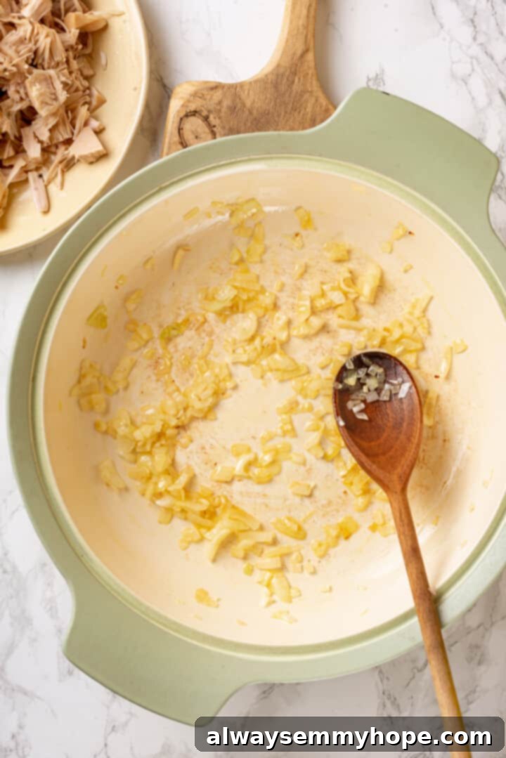 Overhead view of cooked onion in pan with wooden spoon