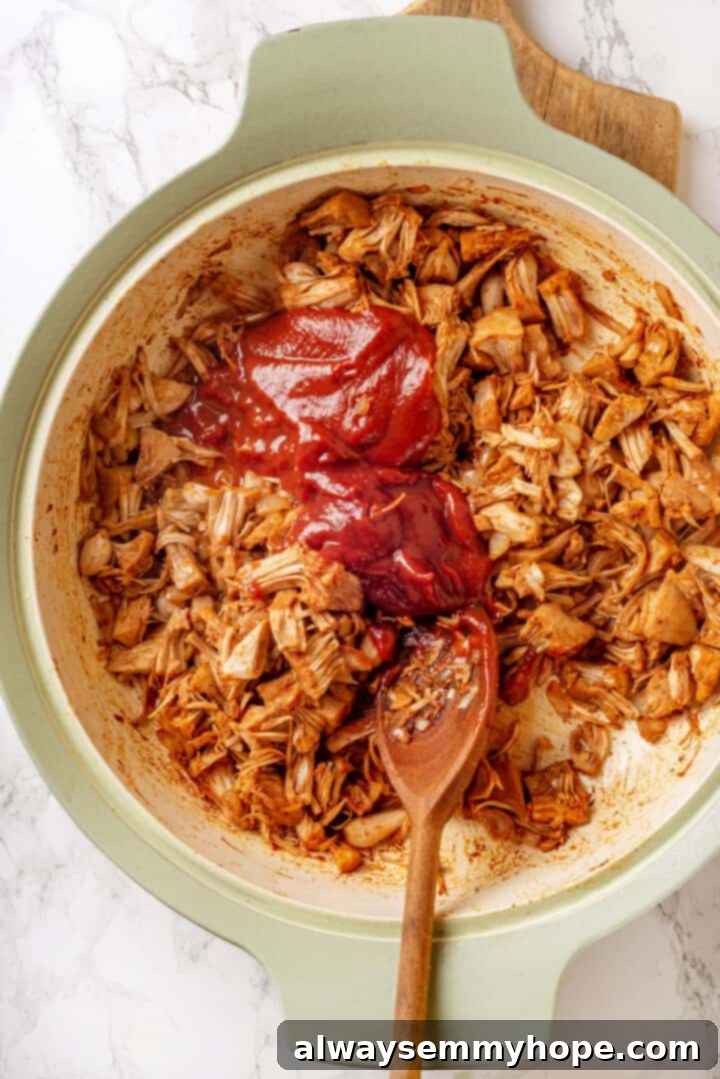 Overhead view of barbecue sauce added to pan of jackfruit taco filling