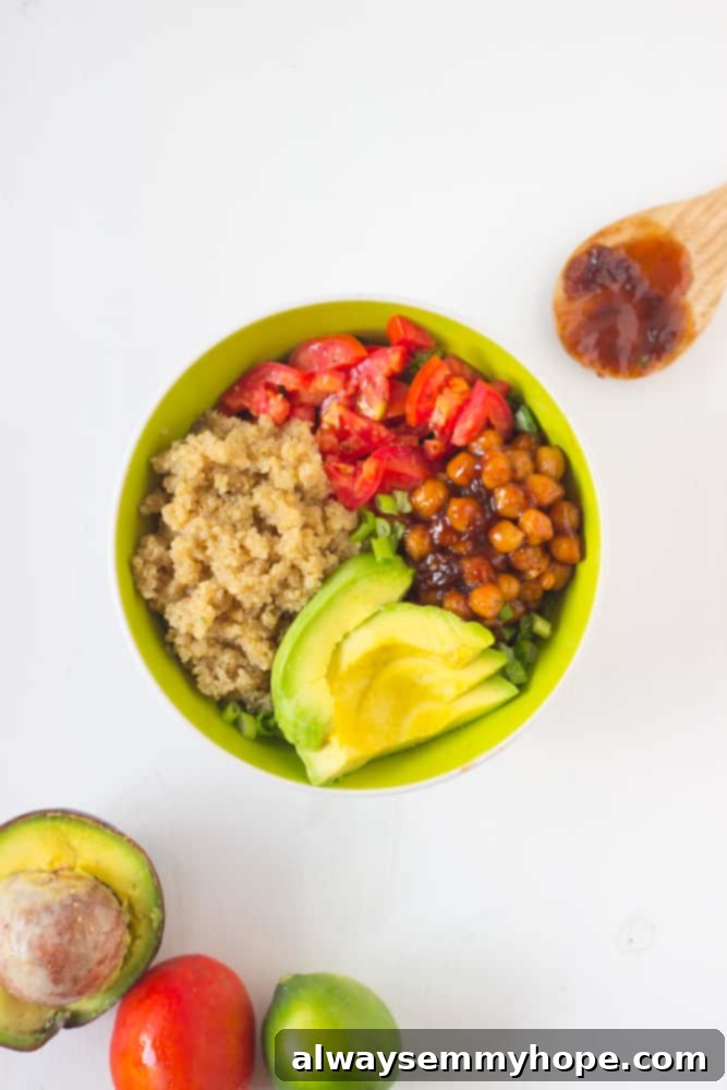 Discover the mouth-watering Tropical Quinoa Salad Bowl with BBQ Chickpeas, loaded with fresh avocados, tomatoes, and scallions for a nutritious, filling, and utterly delicious lunch or dinner! Honey & lime quinoa salad bowl with spicy BBQ chickpeas in a green bowl. A close-up shot showcasing the vibrant ingredients.