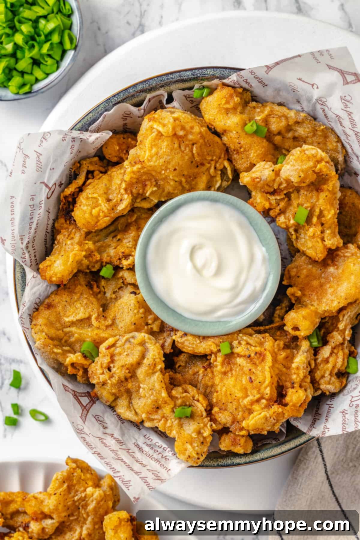 Indulge in crispy, delicious vegan fried chicken featuring the unique meaty texture and flavor of oyster mushrooms. Overhead view of crispy vegan fried chicken in a rustic bowl, served with a creamy dipping sauce on the side.