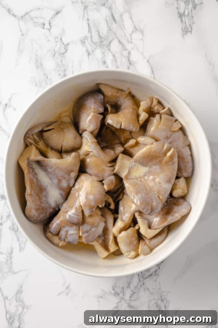 Mushrooms soaking in a flavorful vegan buttermilk for ultimate taste. Overhead view of oyster mushrooms marinating in a bowl of vegan buttermilk mixture.