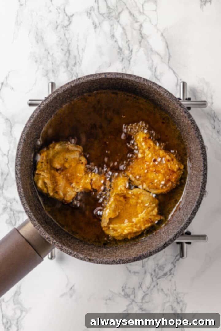 Sizzling vegan fried chicken for that irresistible crunch. Overhead view of several pieces of vegan fried chicken sizzling in hot oil in a saucepan.