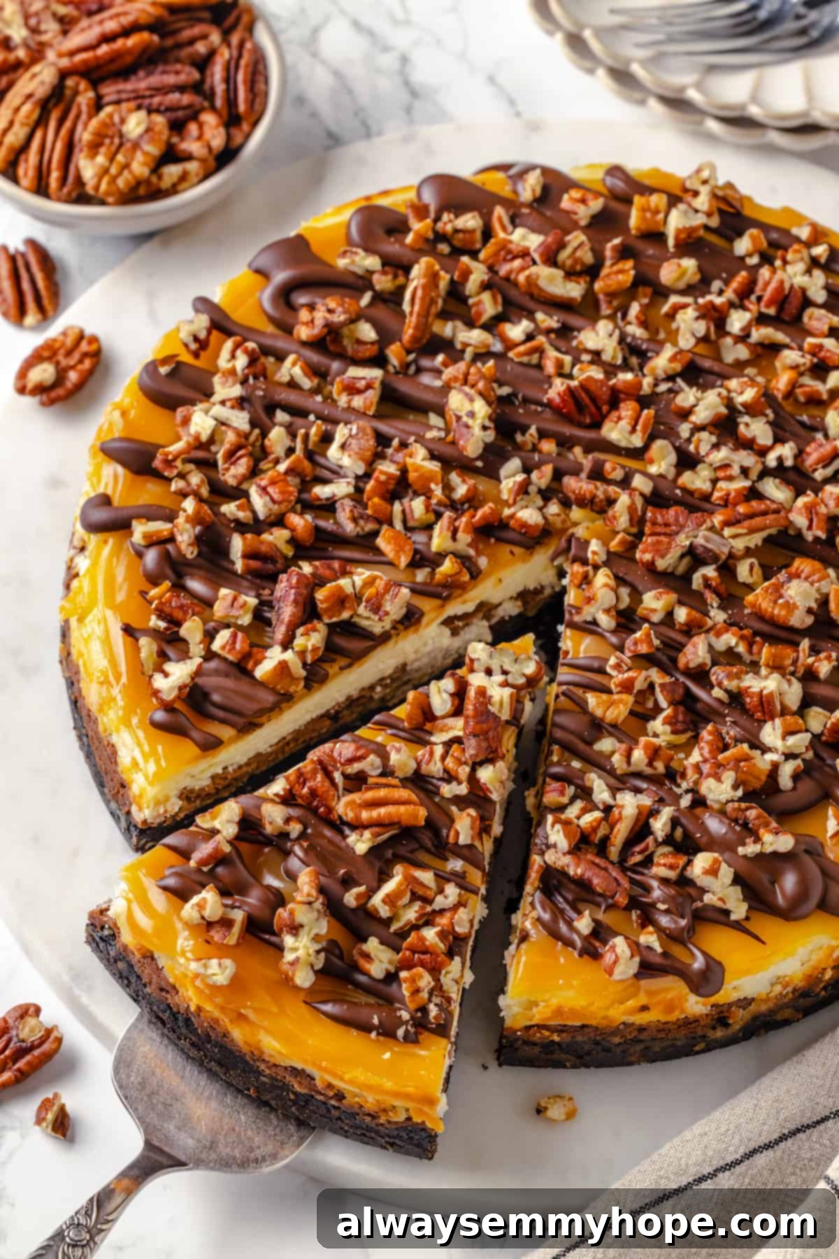 Top down view of turtle cheesecake on platter with slice being pulled away