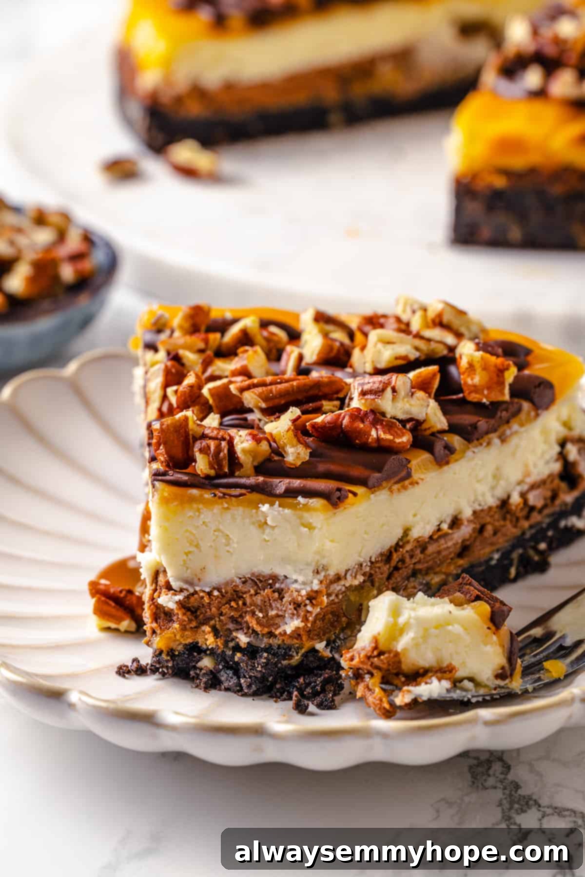 Slice of turtle cheesecake on plate with forkful of cake set to side
