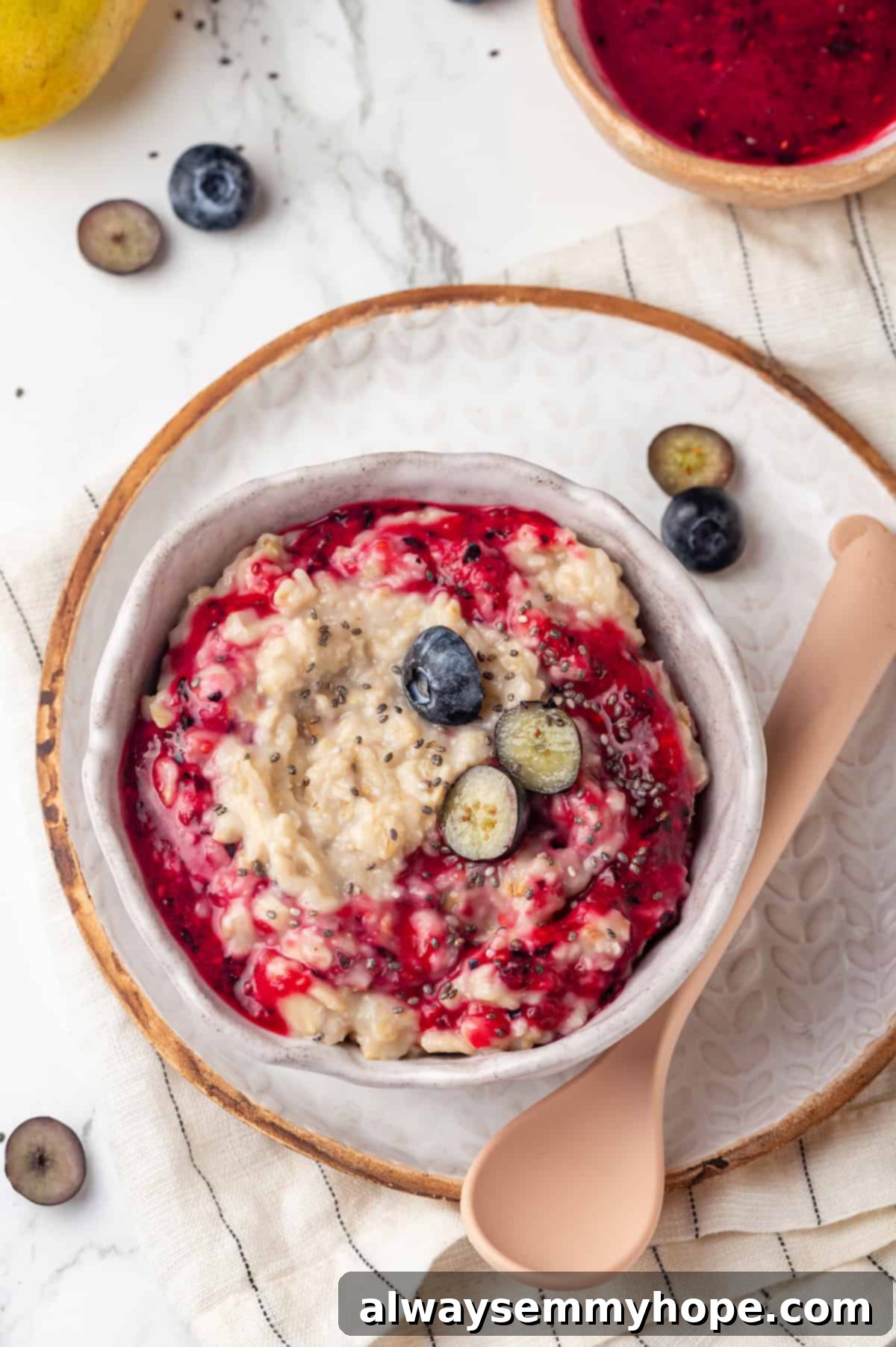 Overhead view of a beautiful bowl of baby oatmeal, topped with colorful fruits, placed on a decorative plate.